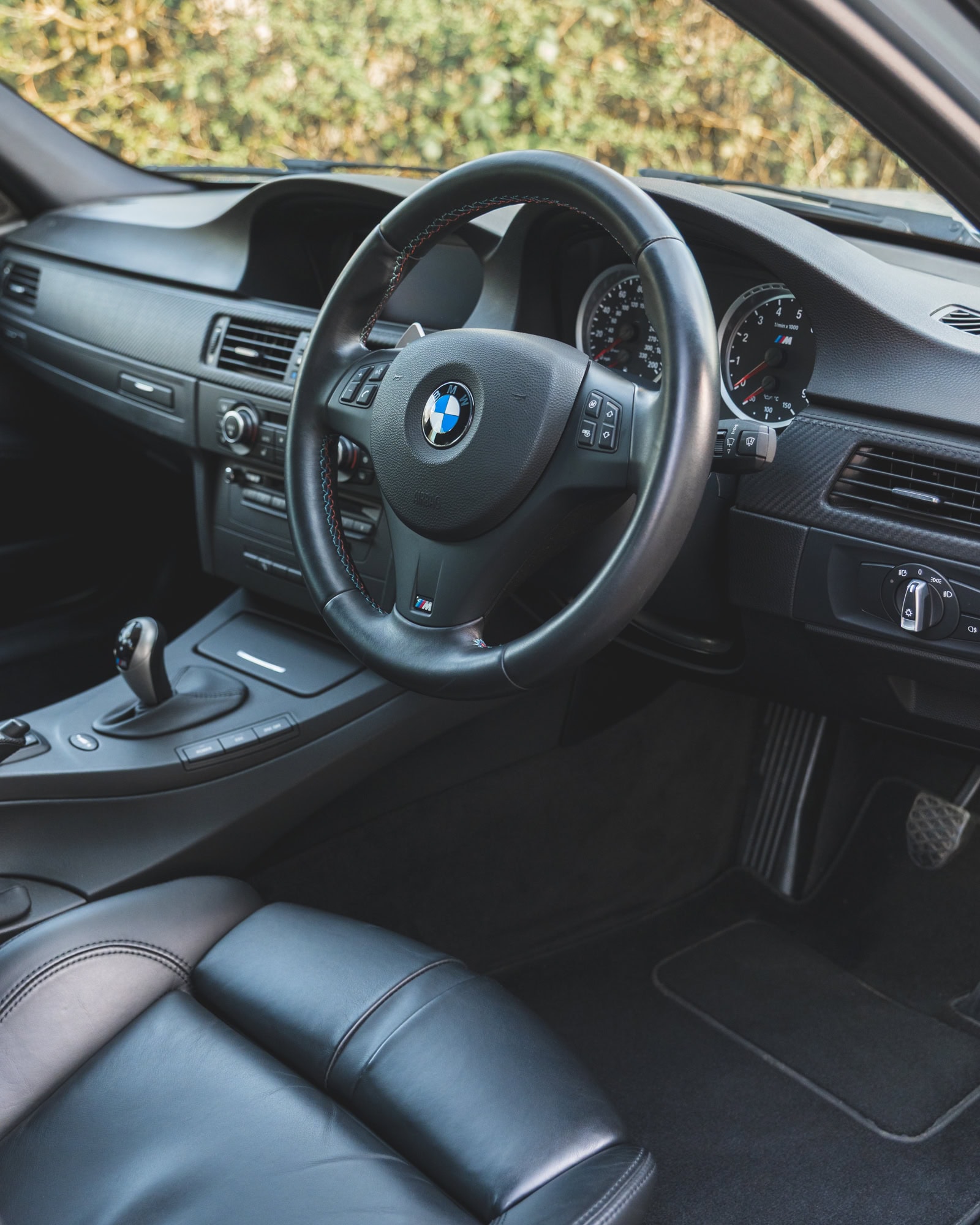 BMW E90 M3 interior showing steering wheel centre console DCT gearbox and black leather seats