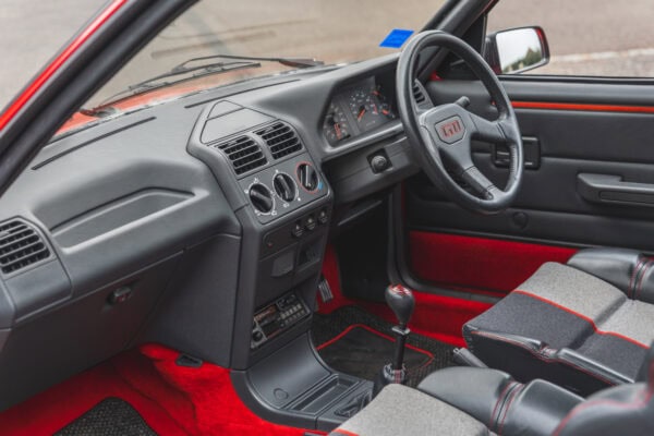 Nearside view into interior of Peugeot 205 GTI showing steering wheel and centre console