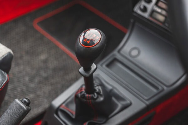 Gear stick on Peugeot 205 GTI with red trimmed car mats in the background