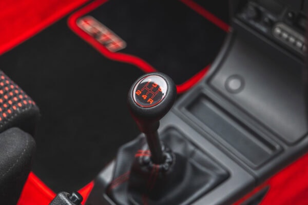 Close up view of gear knob on Peugeot 205 GTI show red and black floor mats in the background