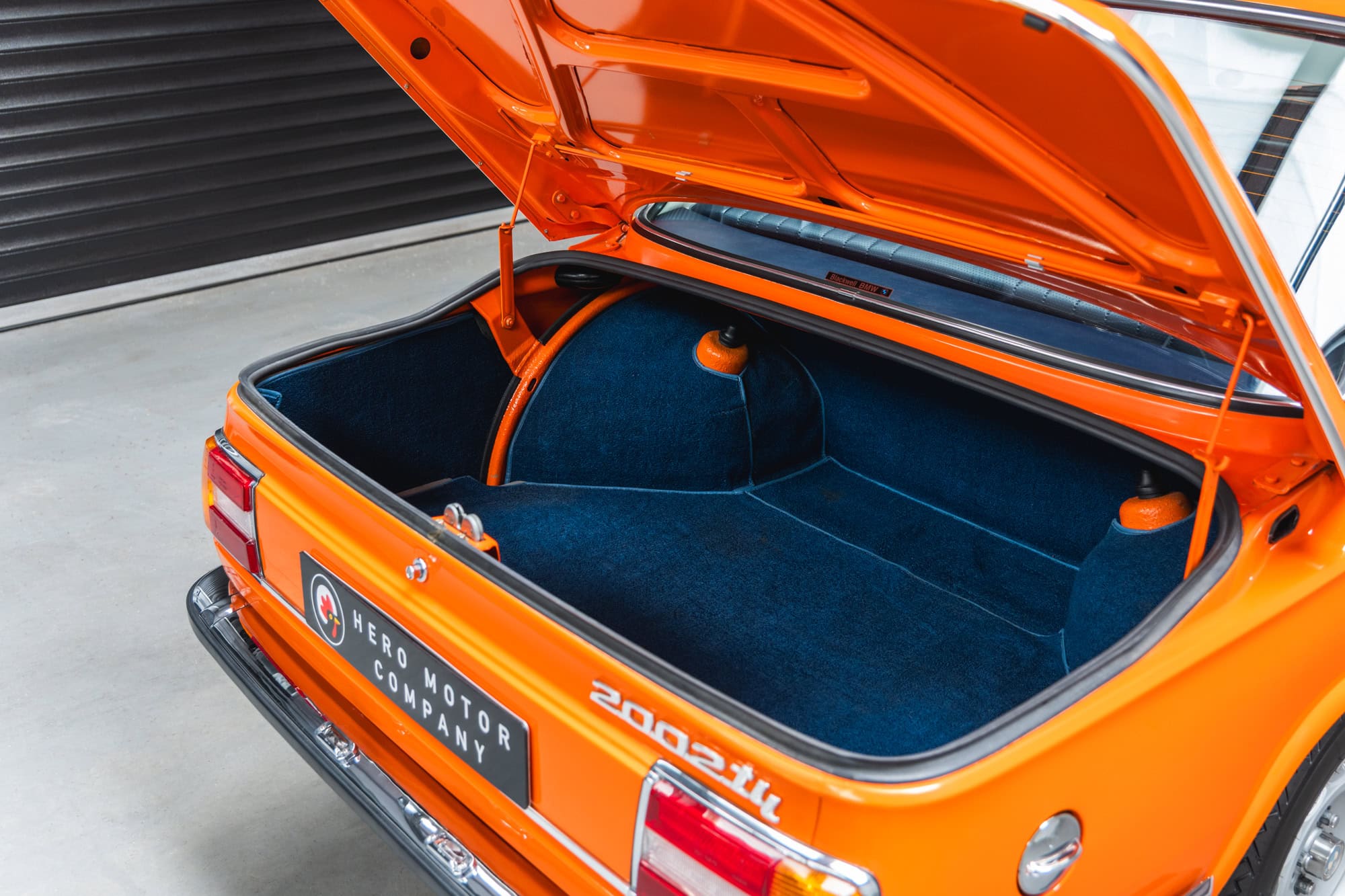 The open boot of a 1975 Inka Orange BMW 2002 tii.