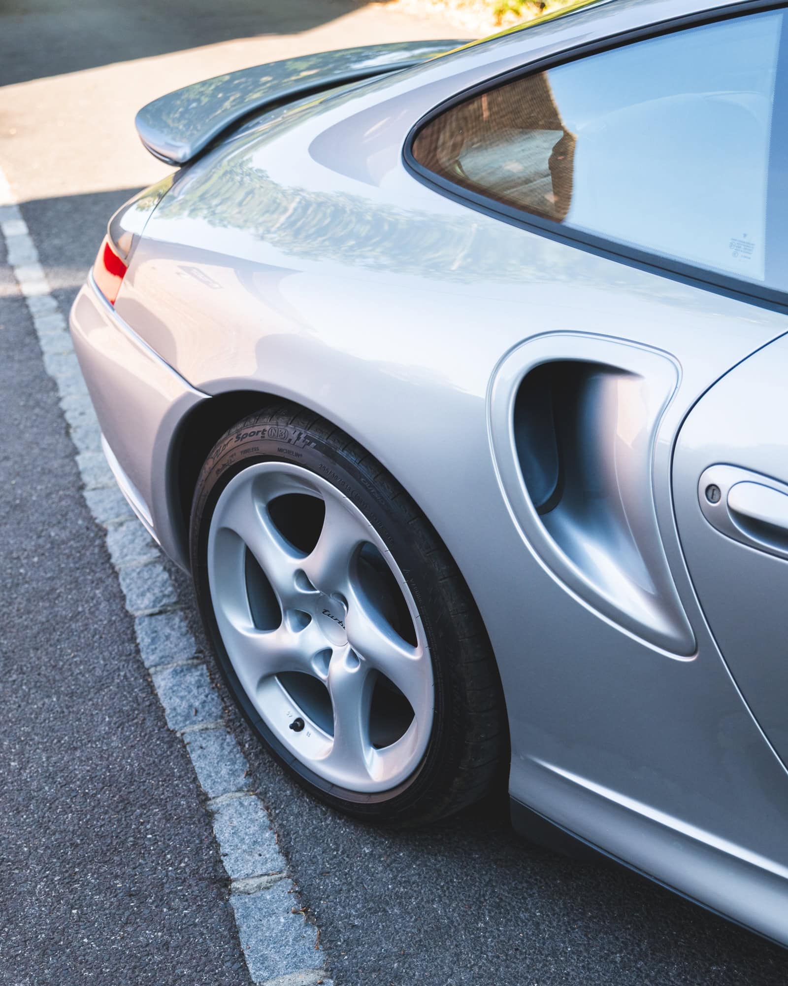 Rear quarter and air intake vents of a silver Porsche 996 Turbo.