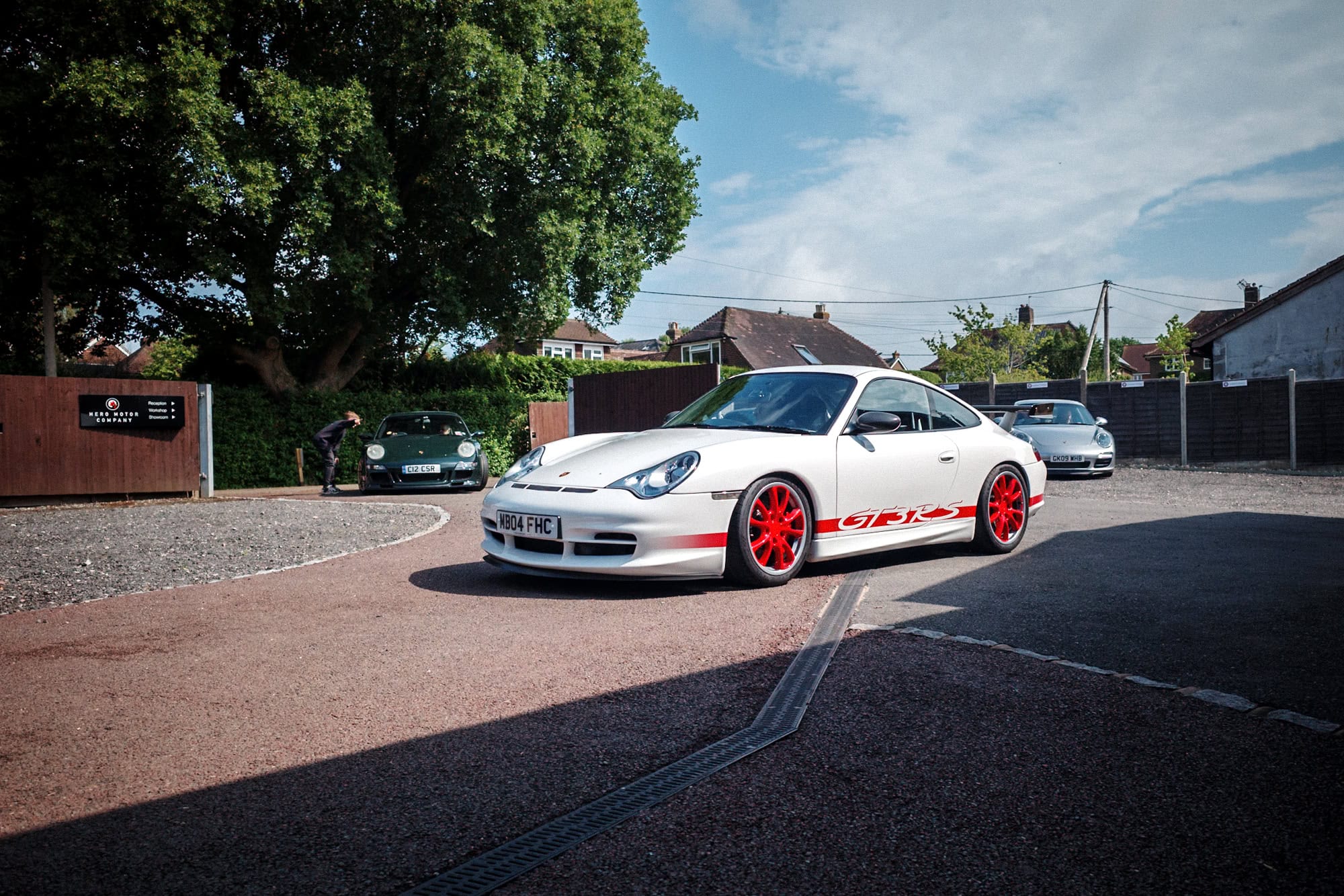 A white Porsche 996 GT3 RS with red wheels.