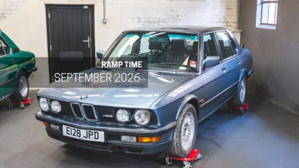 A blue BMW E28 M5 in a workshop.