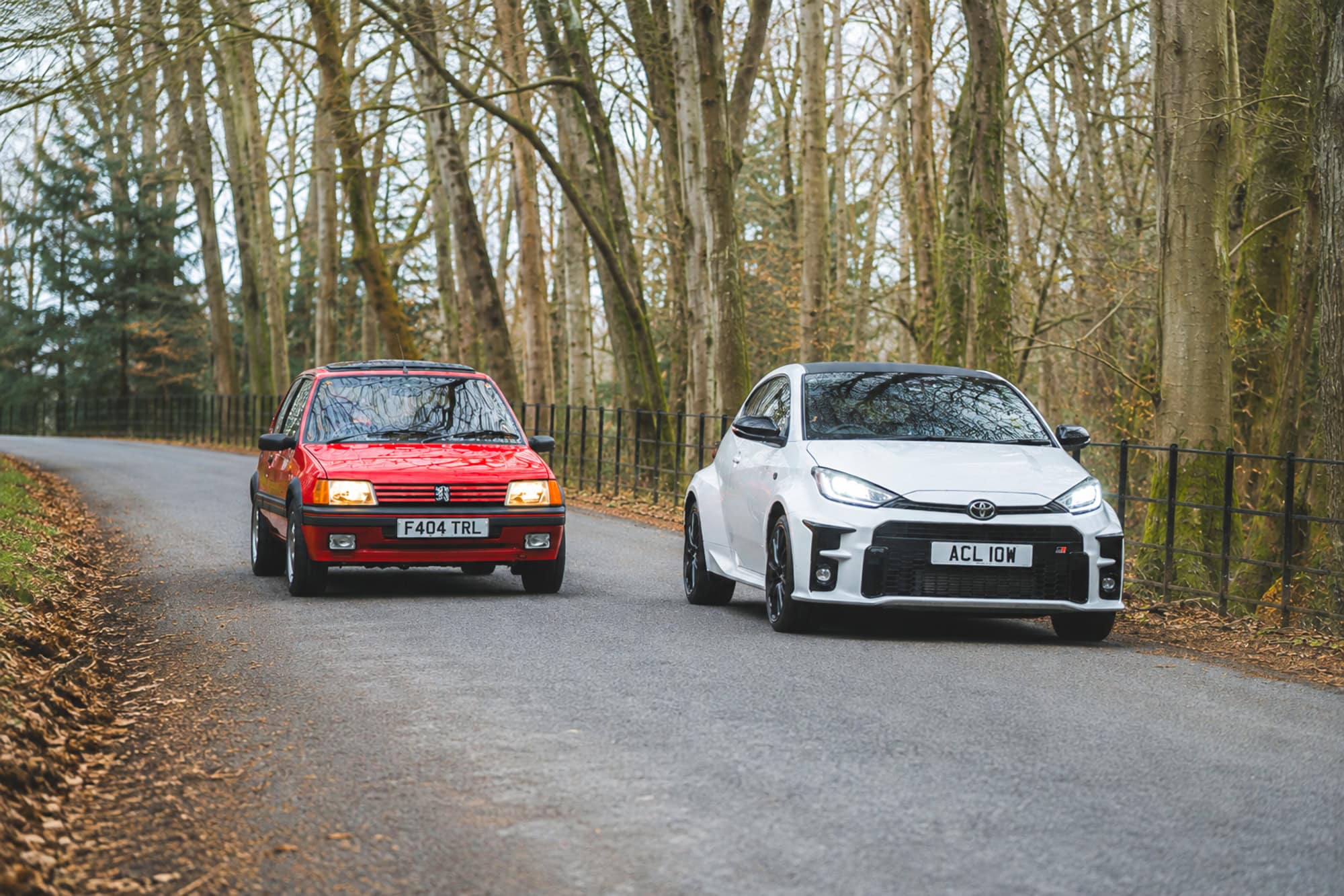 A Peugeot 205 GTI and a Toyota Yaris GR Four racing down a country road.