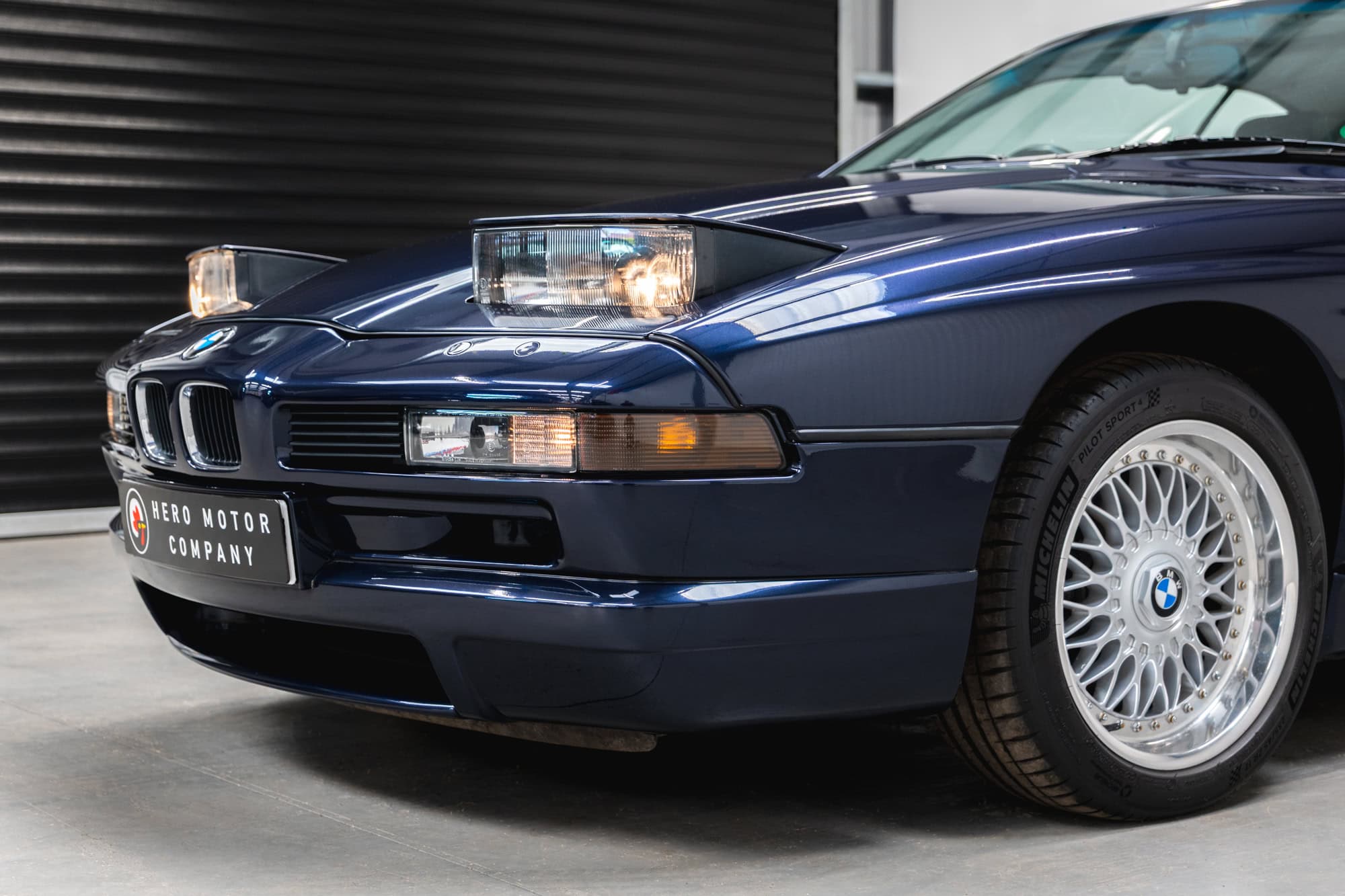 Pop-up headlights on a BMW 850 CSI coupe in orient blue metallic with BBS split rim alloy wheels.
