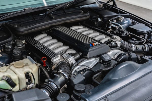 The engine bay of a 1994 BMW 850 CSI coupe in orient blue metallic with a V10 engine.